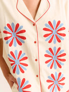 Beige shirt with red and blue floral patterns on a white background