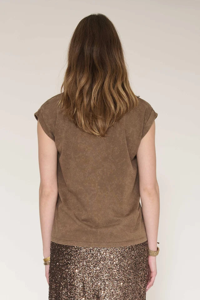 A woman viewed from behind wearing a brown short-sleeve top and a sparkly bronze sequined skirt against a plain light background.