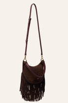 A dark brown suede crescent-shaped shoulder bag with a long fringe bottom, a matching adjustable shoulder strap, and gold-tone hardware, shown against a plain off-white background.