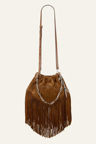 Brown suede handbag with fringes and a chain detail on a beige background