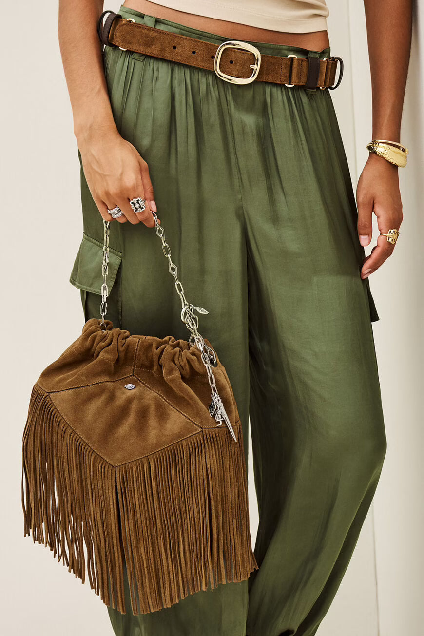A person wearing olive green wide-leg pants and a brown belt, holding a brown suede fringe bucket bag with a silver chain strap.