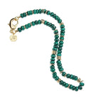 A beaded necklace featuring dark green malachite beads separated by small gold spacer rings, with a gold lobster clasp and a circular gold brand tag engraved with 'JW'.