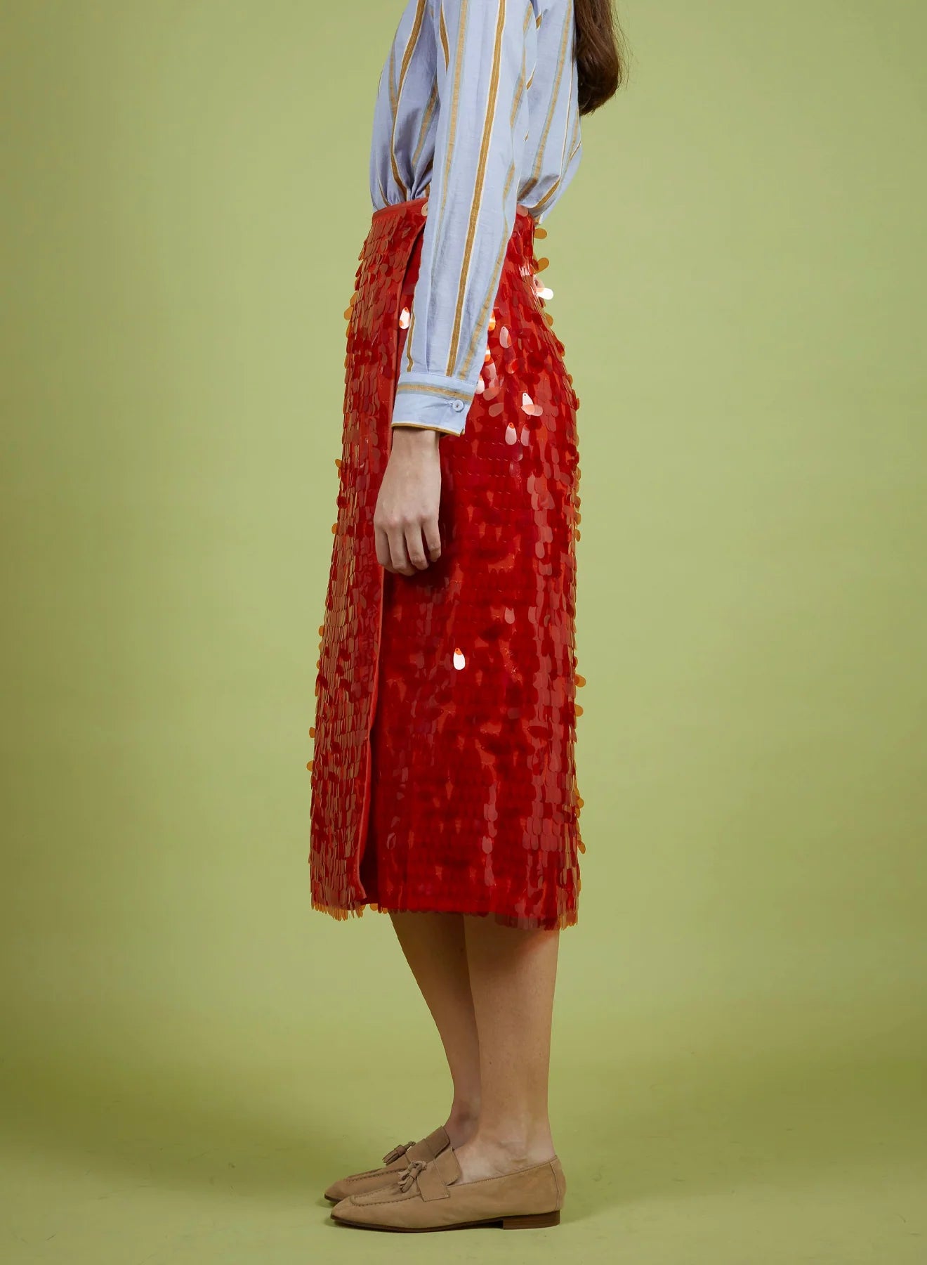 Person wearing a red sequin skirt on a green background
