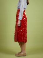 Person wearing a red sequin skirt on a green background