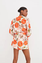Woman wearing a floral dress with orange flowers on a white background