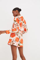 Woman wearing a floral outfit with orange and green flowers on a white background