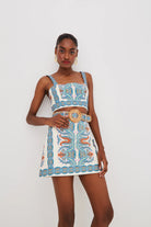 Woman wearing a patterned two-piece outfit with a belt on a white background