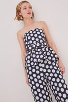 Woman wearing a strapless polka dot dress against a plain background
