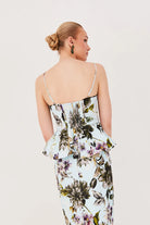 Woman wearing a floral dress with thin straps on a plain background