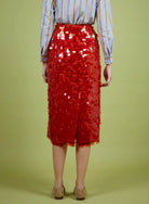 Person wearing a red sequin skirt on a green background