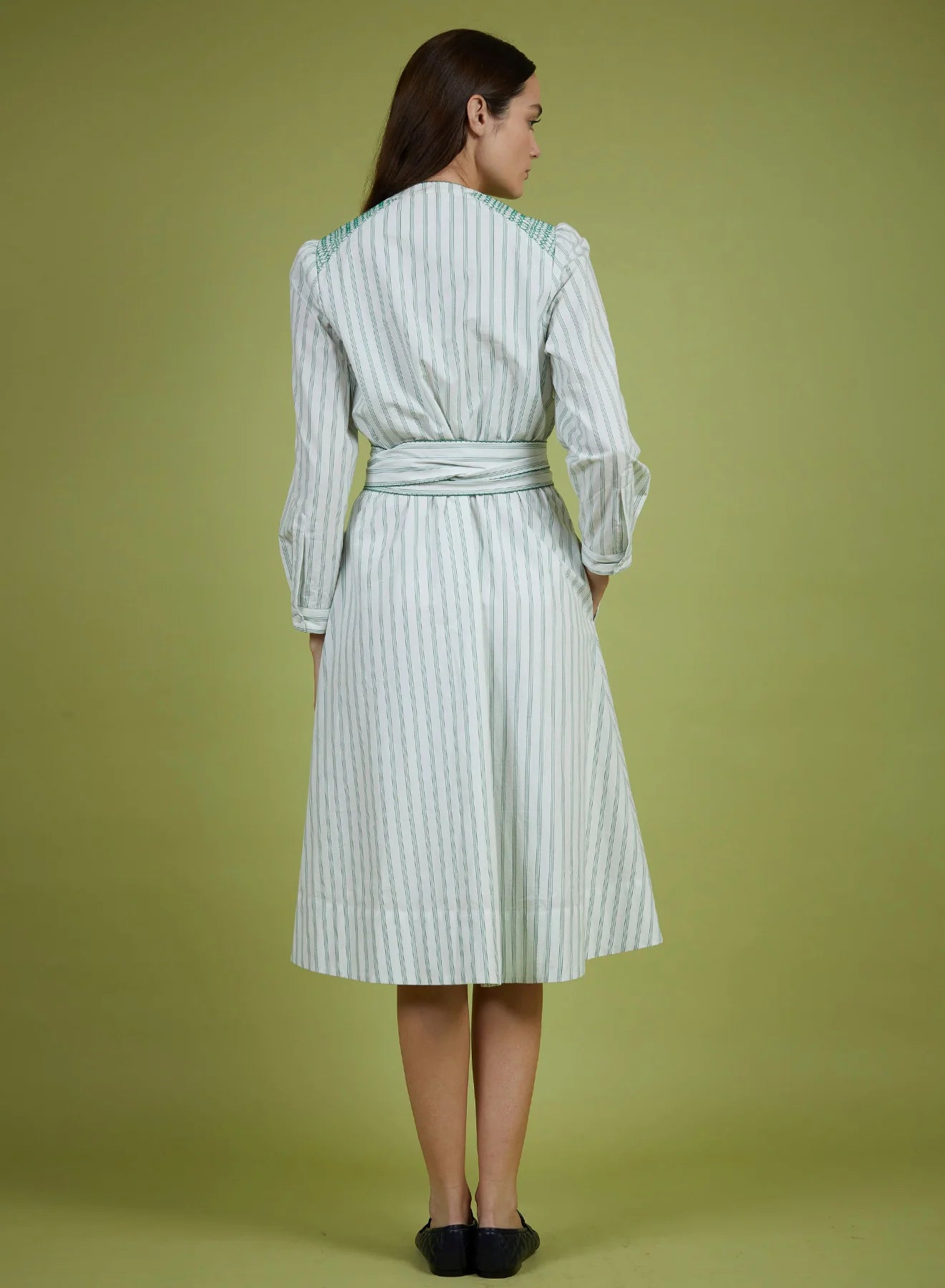 Woman wearing a green and white striped dress against a solid background
