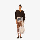 Woman wearing a brown top and patterned skirt on a white background