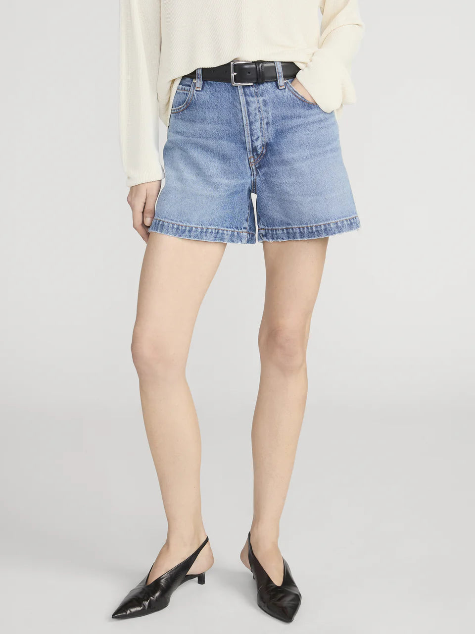 Person wearing light blue denim shorts on a plain background