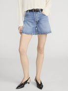 Person wearing light blue denim shorts on a plain background