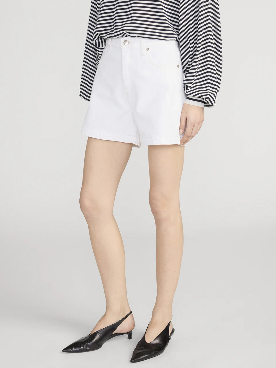 Person wearing white shorts with a black and white striped shirt on a light gray background