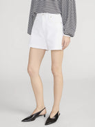 Person wearing white shorts with a black and white striped shirt on a light gray background