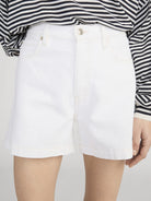 White shorts worn with a black and white striped shirt on a plain background