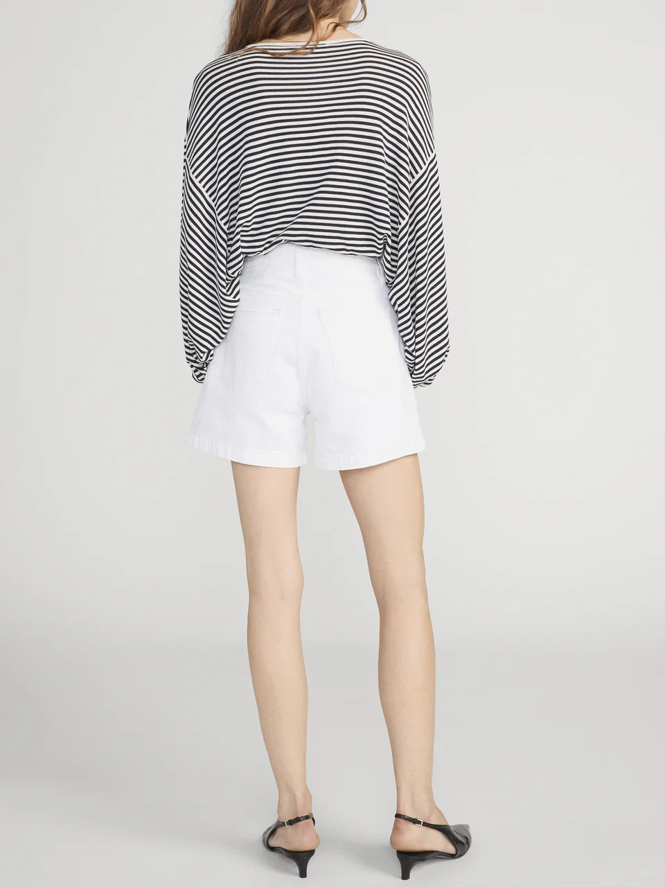 Person wearing a black and white striped shirt and white shorts on a plain background