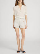 Woman wearing a cream blouse and striped shorts on a white background