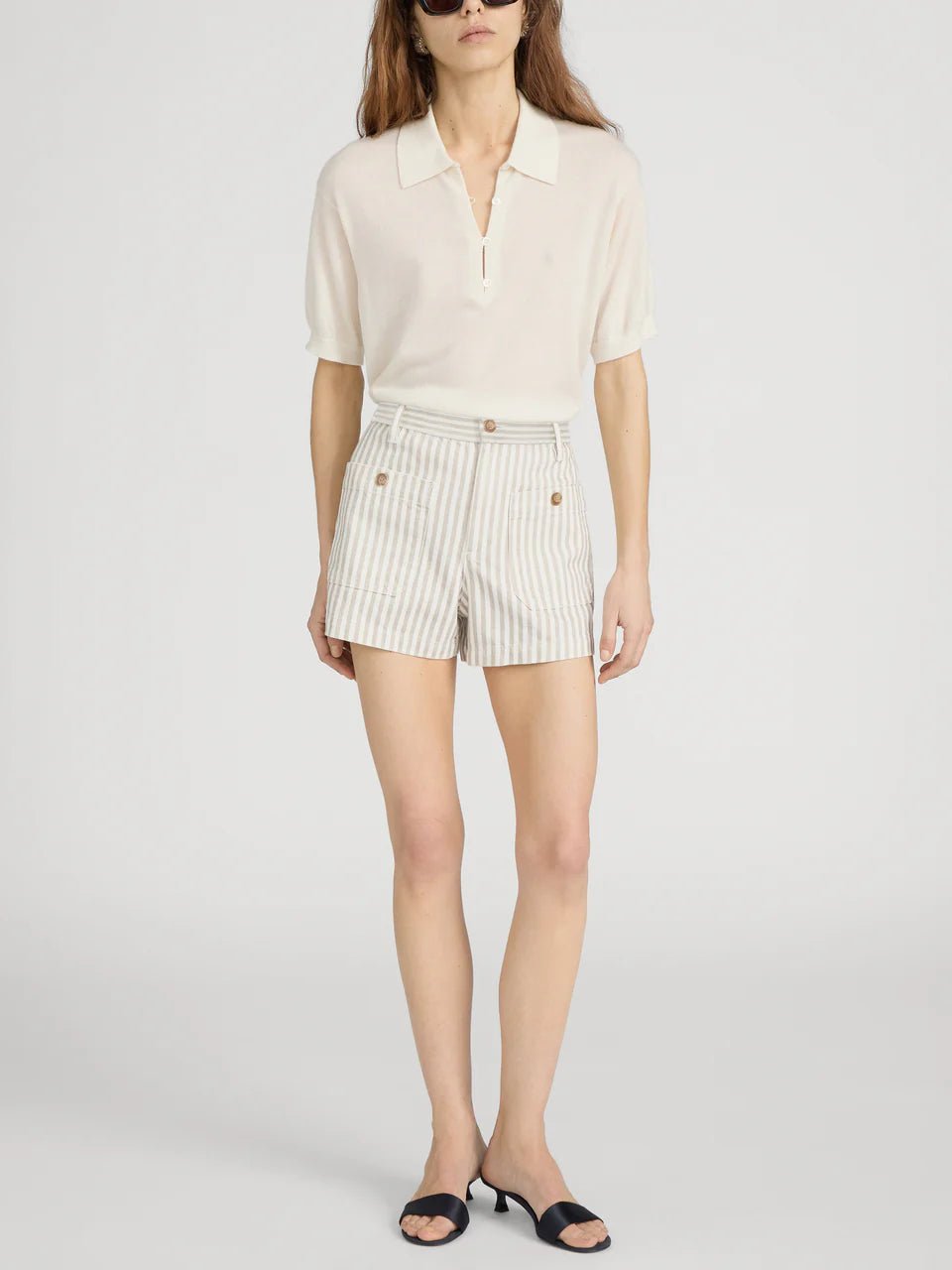 Woman wearing a cream blouse and striped shorts on a white background