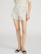 Person wearing white shorts with black stripes on a light gray background
