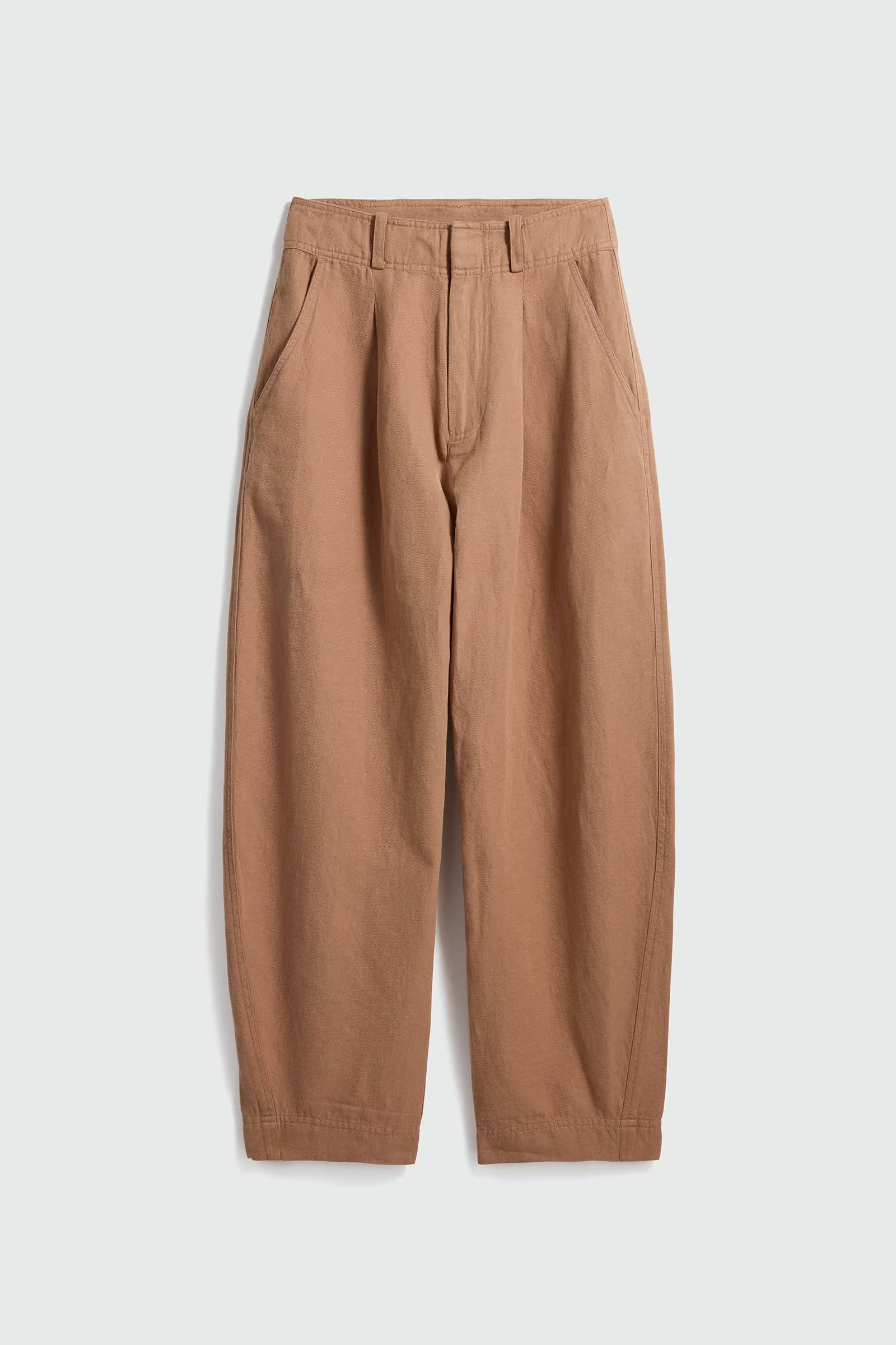 A pair of relaxed-fit trousers in a warm tan or camel color, featuring a pleated front and side pockets, laid flat against a light gray background.
