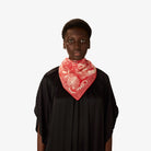 Person wearing a black garment with a red and white patterned scarf on a white background
