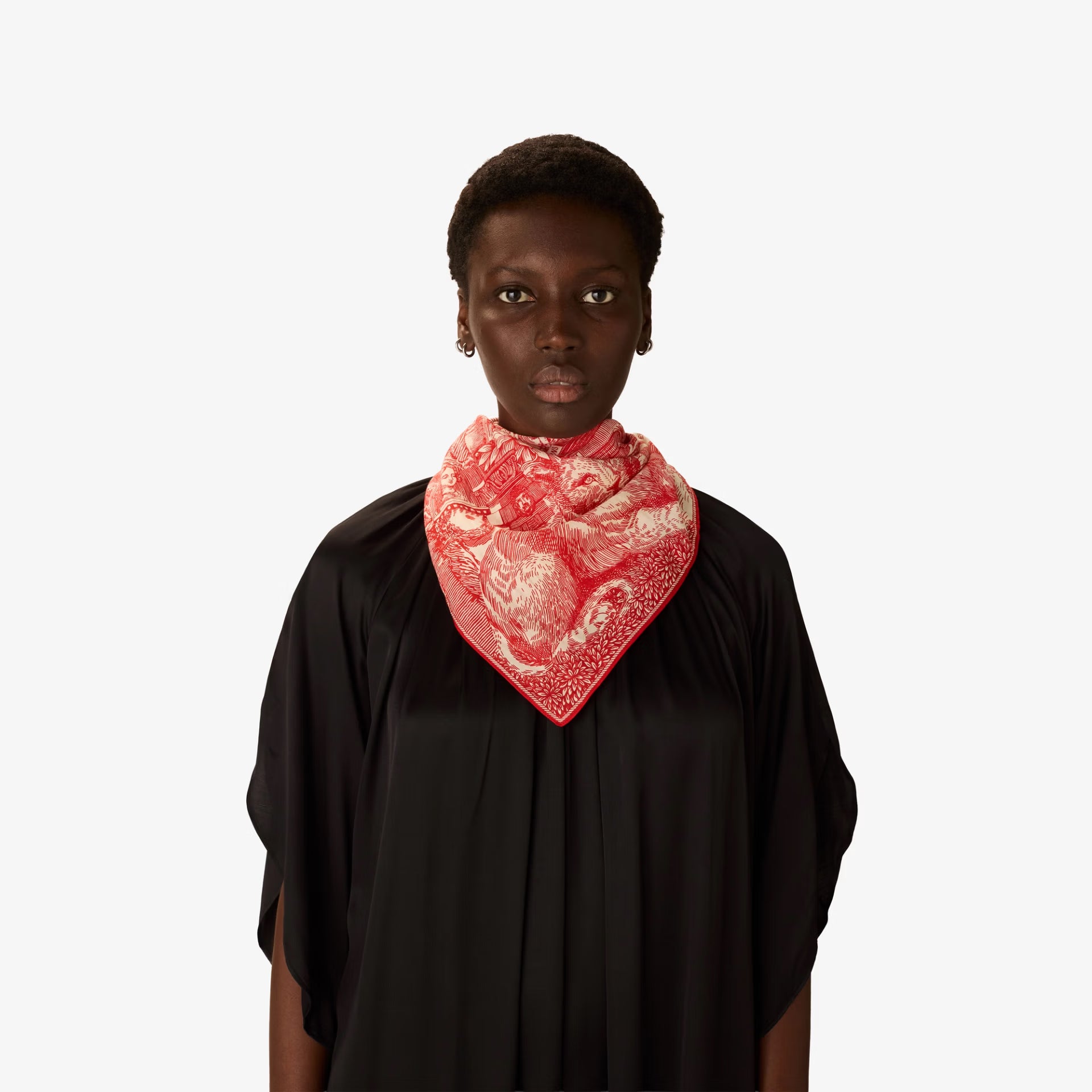 Person wearing a black garment with a red and white patterned scarf on a white background