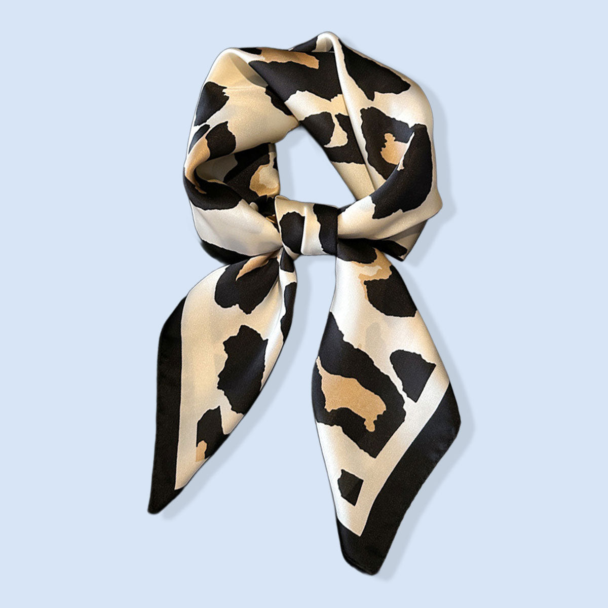 Leopard print scarf tied in a bow on a light blue background