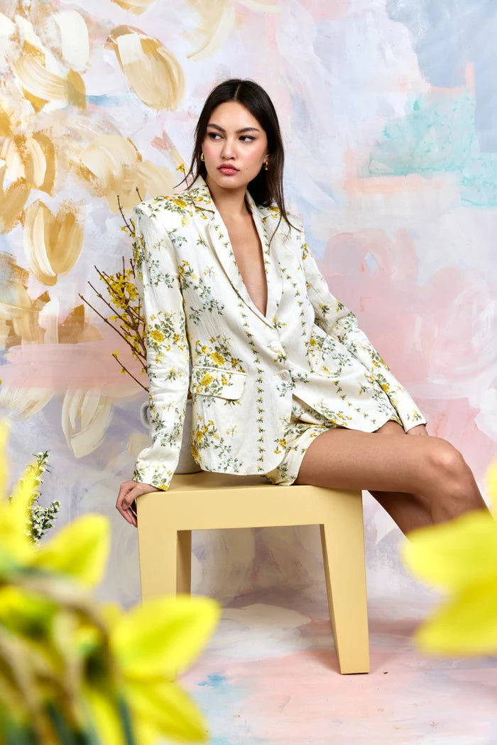 Woman in a floral outfit sitting on a stool with a colorful, abstract background