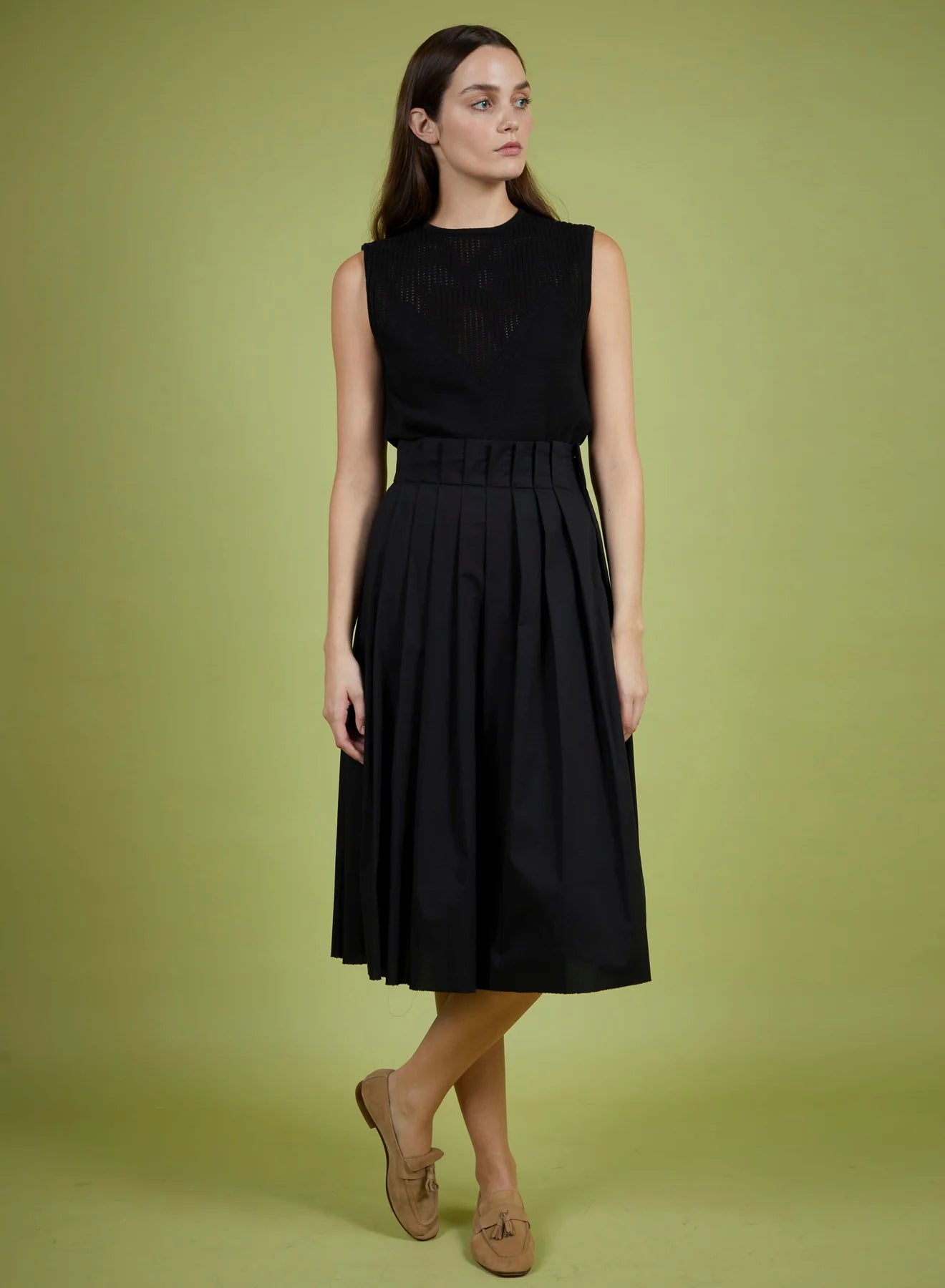 Woman wearing a black sleeveless dress on a green background