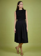 Woman wearing a black sleeveless dress on a green background