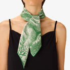 Person wearing a green and white patterned scarf on a plain background