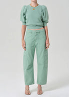 Person wearing a mint green outfit with a top and pants on a white background