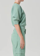 Person wearing a light green outfit on a plain background
