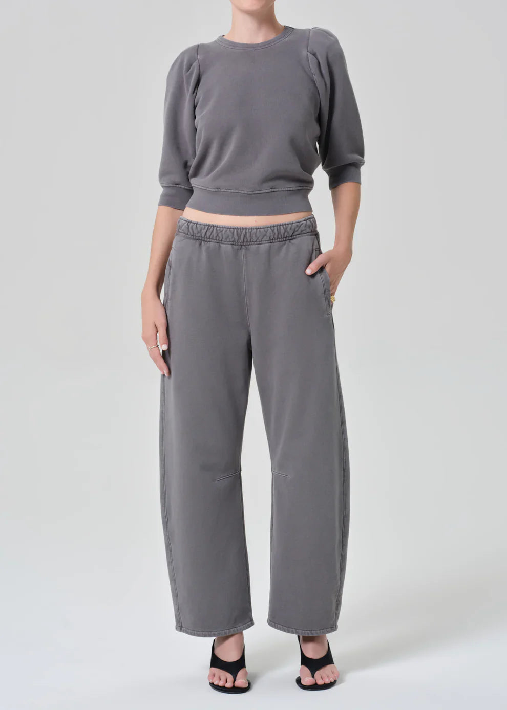 Person wearing a gray outfit with a cropped top and wide-leg pants on a white background