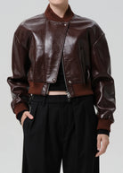 Brown leather jacket worn by a person on a plain background