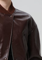 Close-up of a brown leather jacket with a zipper on a plain background