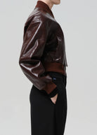 Brown leather jacket worn by a person on a light gray background