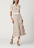 Woman wearing a patterned dress with a white belt on a plain background