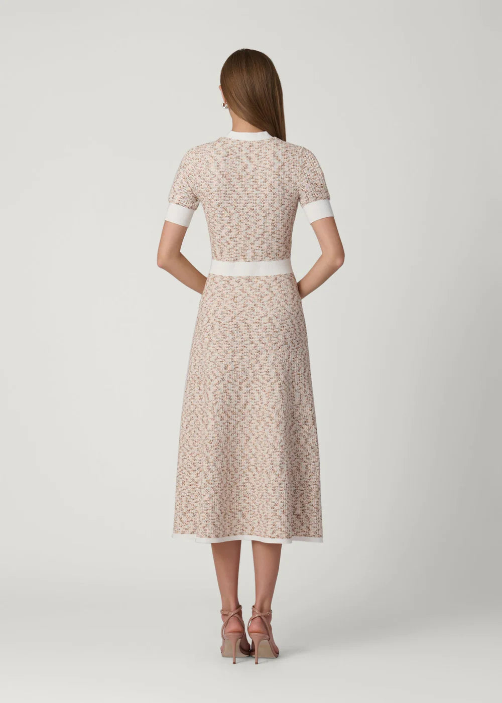 Woman wearing a patterned dress with a white belt on a light gray background