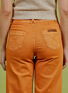 Person wearing orange pants with a visible brand logo on a green background
