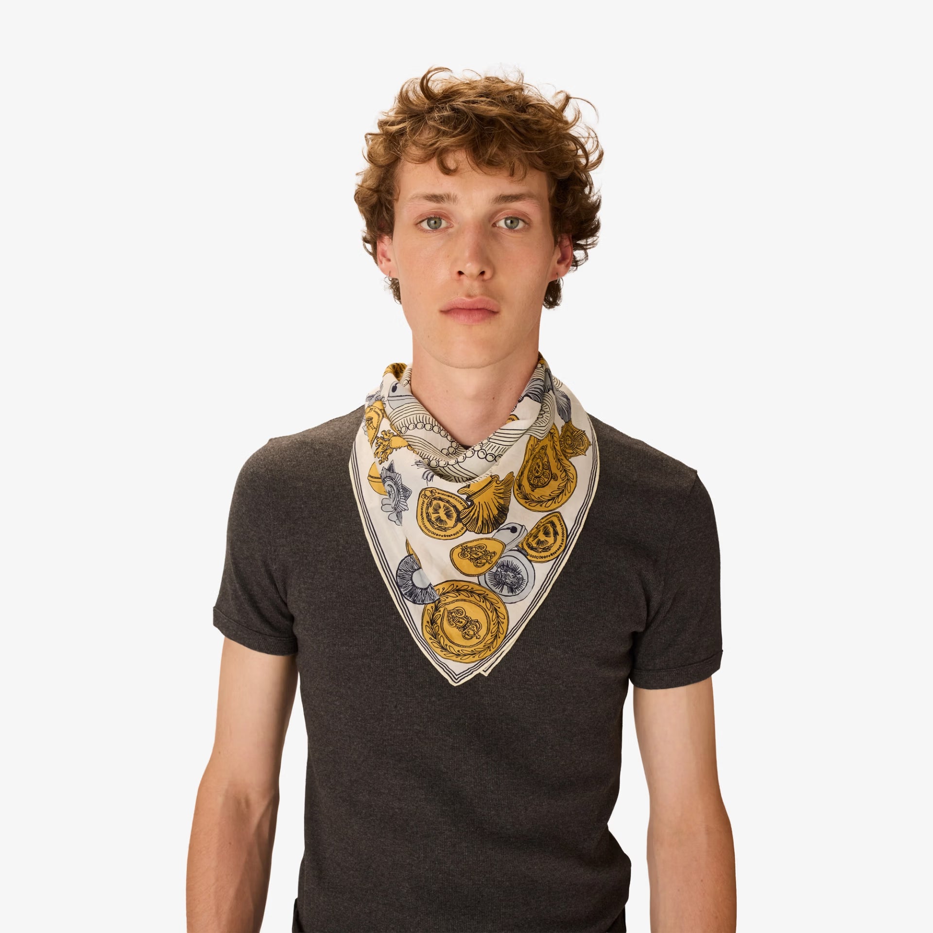 Man wearing a patterned scarf around his neck against a white background