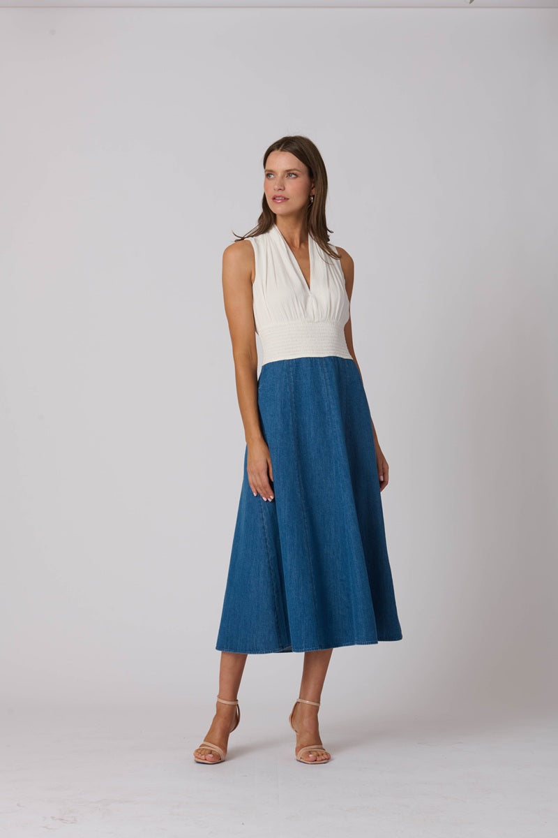 Woman wearing a white top and blue skirt on a plain background