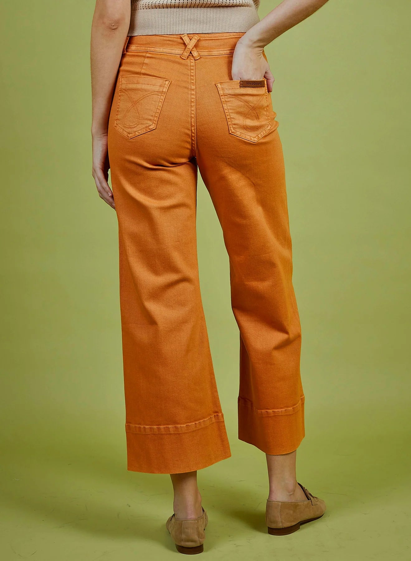 Person wearing orange pants on a green background
