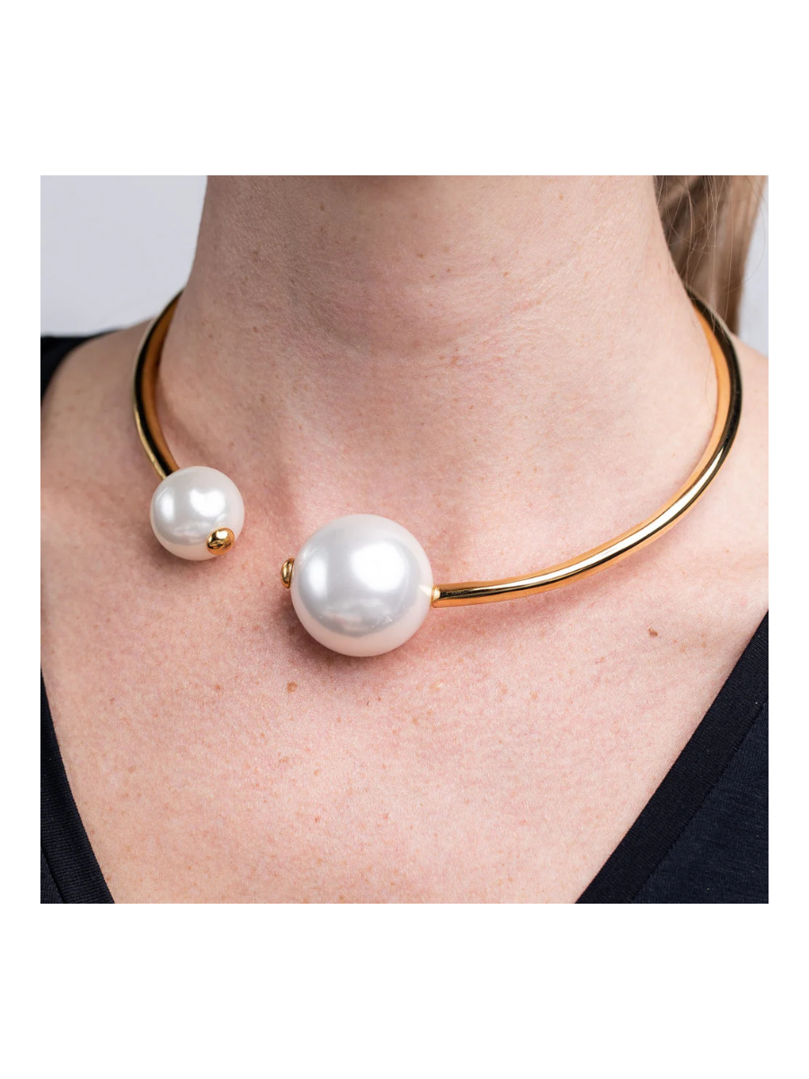 Gold necklace with large white pearls worn by a person on a plain background