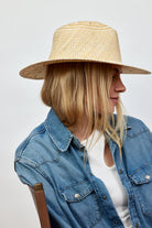 Person wearing a straw hat and denim jacket on a plain background