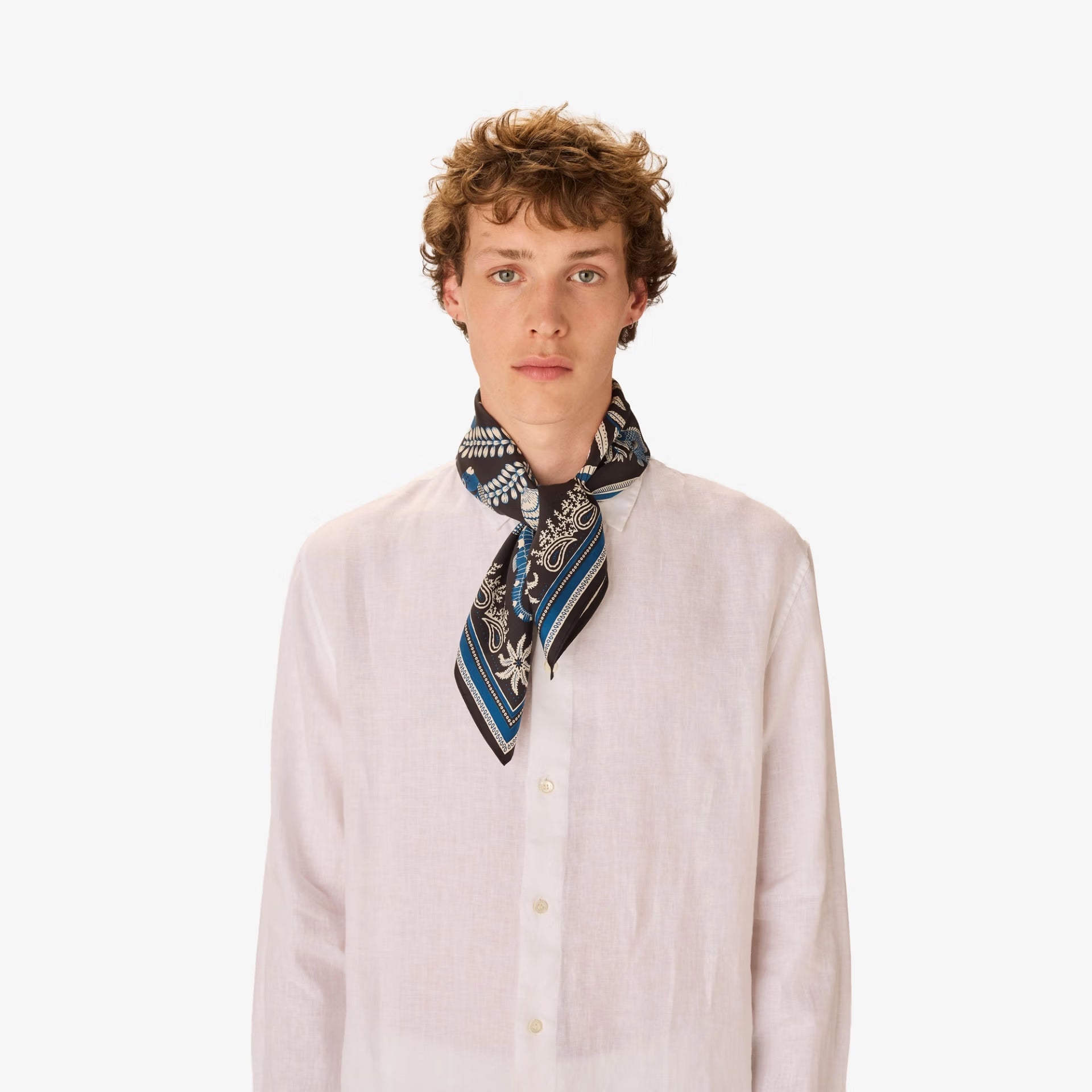 Man wearing a patterned scarf around his neck against a white background