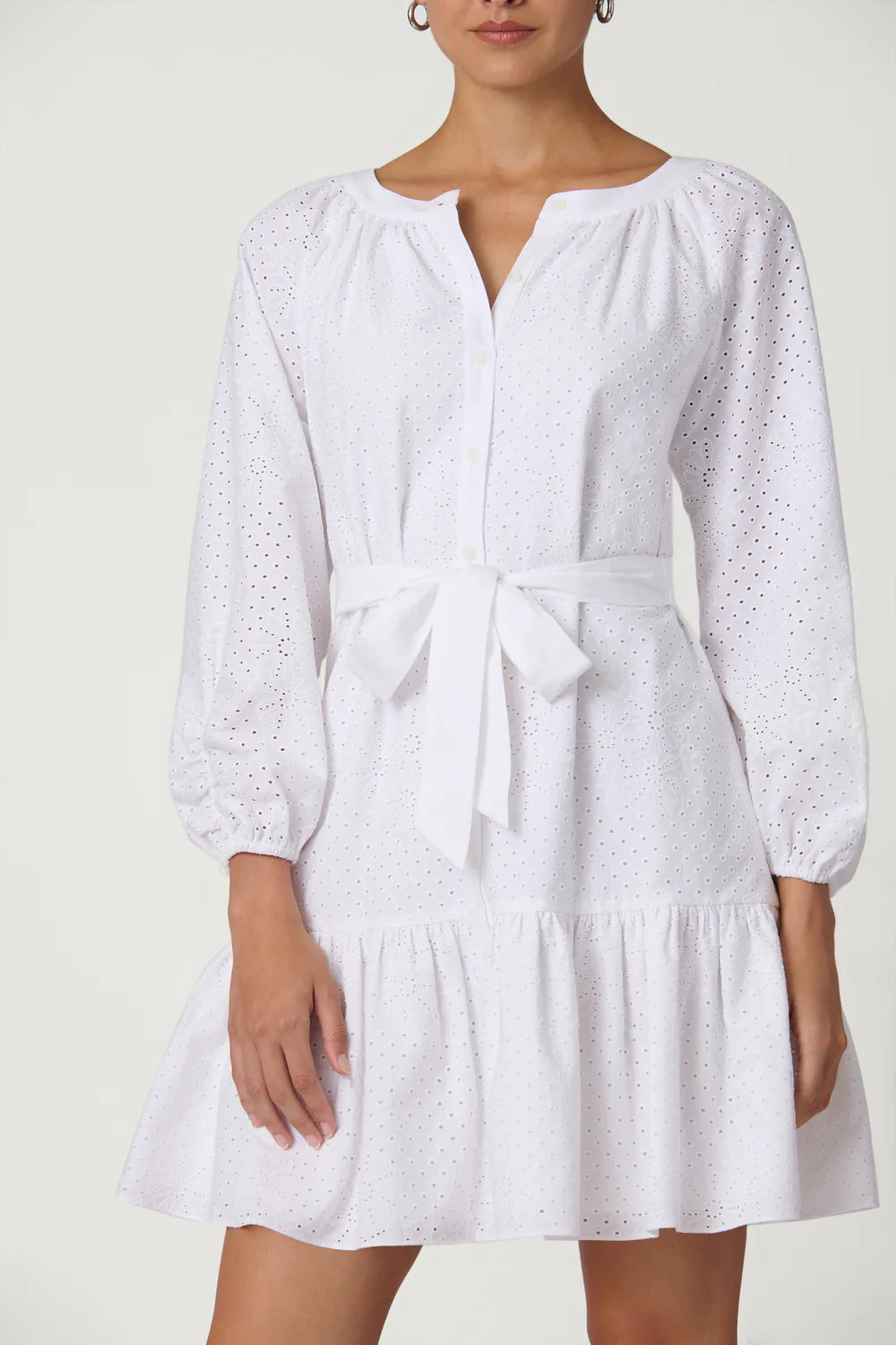 White dress with long sleeves and a tie waist on a plain background