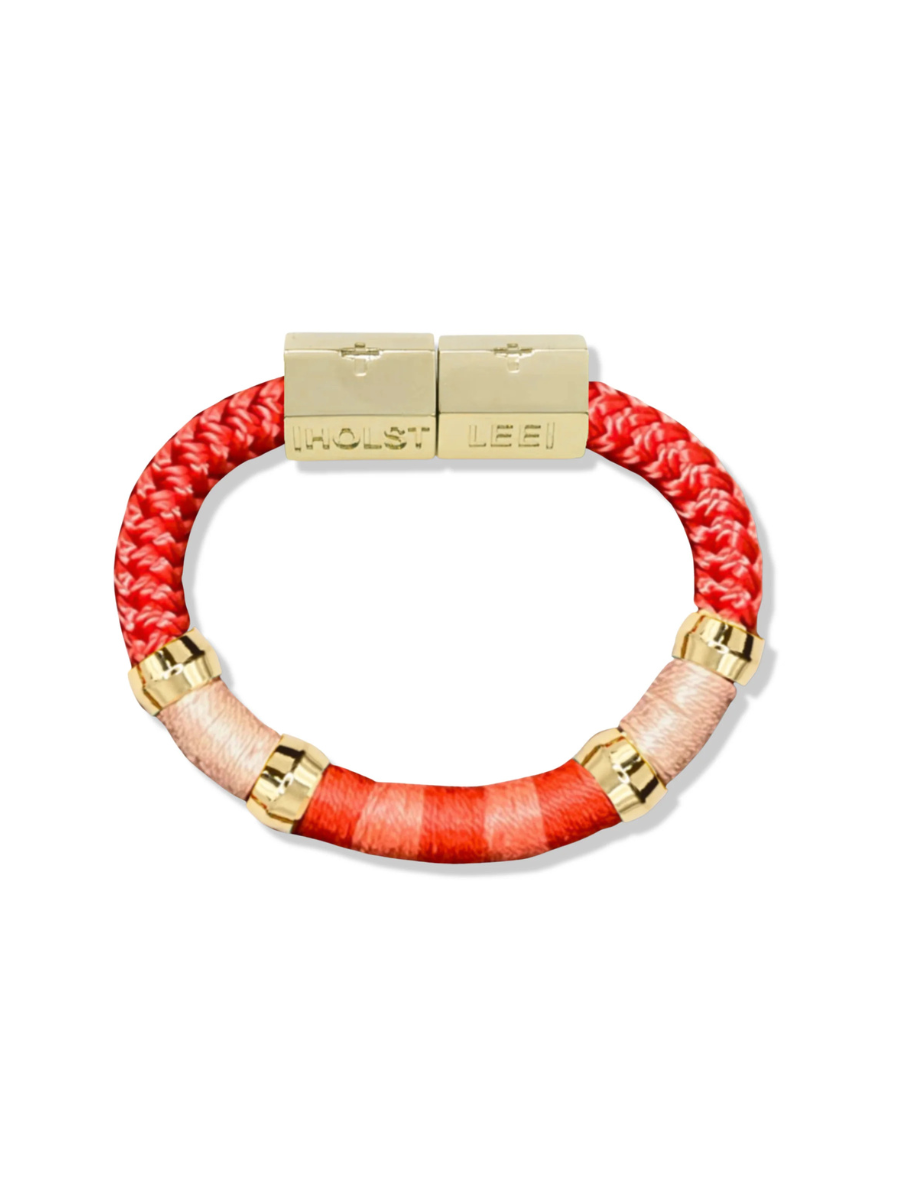 Bracelet with red and beige braided design and gold accents on a white background